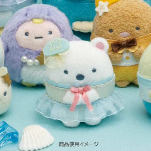 Plush toys with a focus on a white plush toy with a blue dress and pink bow, surrounded by other plush toys on a light blue background.